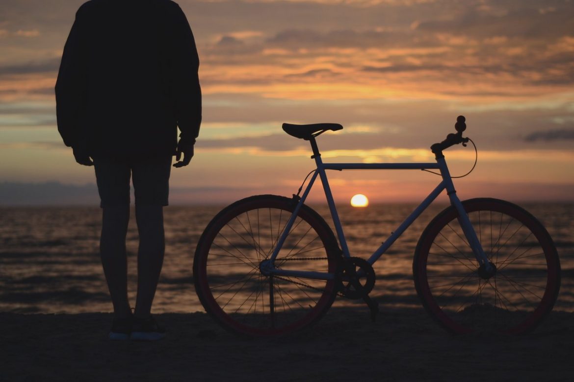 man bicycle beach ocean sunset